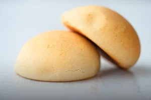 Almojábana valluna tradicional recién horneada, con textura suave y dorada, servida sobre una mesa de madera en Panadería El Molino, Cali.