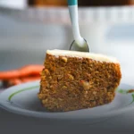 Torta de zanahoria artesanal con trozos de nueces en la parte superior, servida sobre una mesa de madera rústica en Panadería El Molino, Cali.