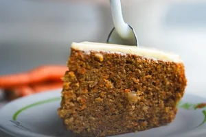 Torta de zanahoria artesanal con trozos de nueces en la parte superior, servida sobre una mesa de madera rústica en Panadería El Molino, Cali.