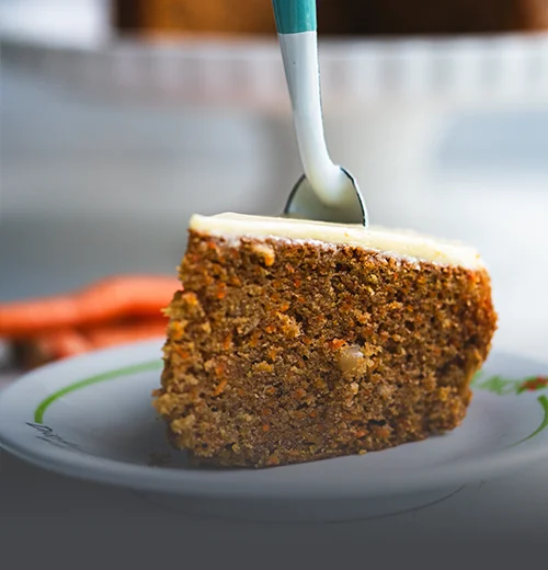 Torta de zanahoria artesanal con trozos de nueces en la parte superior, servida sobre una mesa de madera rústica en Panadería El Molino, Cali.