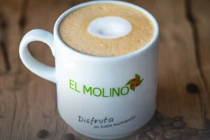 Taza de capuchino artesanal con espuma cremosa y arte latte, servida en Panadería El Molino, Cali, ideal para acompañar amasijos.