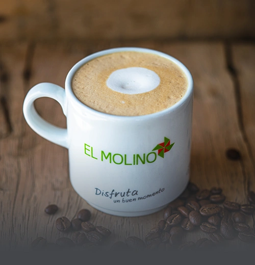 Taza de capuchino artesanal con espuma cremosa y arte latte, servida en Panadería El Molino, Cali, ideal para acompañar amasijos.