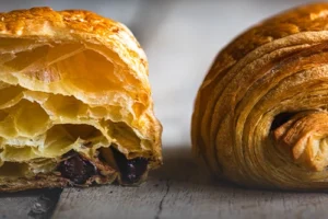 Croissant au chocolat recién horneado, hojaldre francés crujiente relleno de chocolate en Panadería El Molino, Cali.