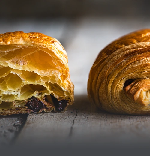 Croissant au chocolat recién horneado, hojaldre francés crujiente relleno de chocolate en Panadería El Molino, Cali.