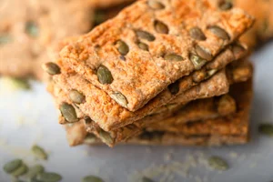 Pan crujiente artesanal con queso emmental fundido y semillas de zapallo, sobre una superficie de madera rústica en Panadería El Molino, Cali.