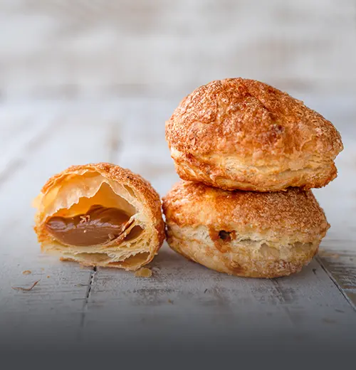 Gloria de Arequipe en Hojaldre - Panadería El Molino Cali Glorias de arequipe artesanales en masa de hojaldre azucarada, mostrando su abundante relleno cremoso, elaboradas en Panadería El Molino, Cali.
