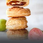 Pila de glorias de guayaba artesanales en masa de hojaldre azucarada, con un corte que muestra su abundante relleno de dulce de guayaba, elaboradas en Panadería El Molino, Cali.