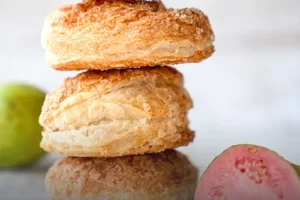 Pila de glorias de guayaba artesanales en masa de hojaldre azucarada, con un corte que muestra su abundante relleno de dulce de guayaba, elaboradas en Panadería El Molino, Cali.