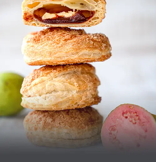 Gloria de Guayaba en Hojaldre - Panadería El Molino Cali Pila de glorias de guayaba artesanales en masa de hojaldre azucarada, con un corte que muestra su abundante relleno de dulce de guayaba, elaboradas en Panadería El Molino, Cali.