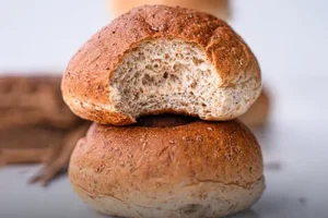 an acema tradicional de salvado y miel, con su característica corteza oscura y rústica, sobre una mesa de madera en Panadería El Molino, Cali.