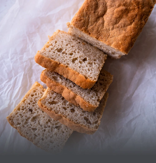 Hogaza y rebanadas de pan de arroz artesanal sin gluten, con miga aireada y corteza dorada, horneado en Panadería El Molino, Cali.