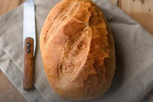 Hogaza de pan campesino artesanal de corteza crujiente, recién horneado en Panadería El Molino, Cali.