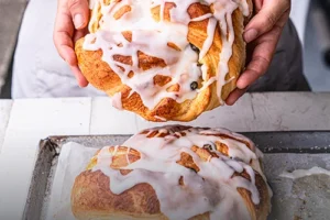 Pan danés artesanal con capas de hojaldre dorado y acabado brillante, servido sobre una mesa de madera en Panadería El Molino, Cali.