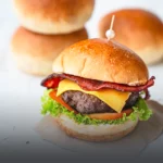 Pan de hamburguesa tipo brioche de papa artesanal, con textura suave y dorada, resaltando la calidad del pan en una hamburguesa armada en Panadería El Molino.