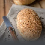 Hogaza de pan francés campo artesanal cubierto con semillas de ajonjolí y linaza, recién horneado en Panadería El Molino, Cali.