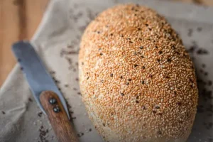Hogaza de pan francés campo artesanal cubierto con semillas de ajonjolí y linaza, recién horneado en Panadería El Molino, Cali.