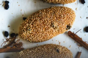 Pan integral artesanal con canela y pasas, tajado sobre una tabla de madera rústica, mostrando su miga suave y nutritiva en Panadería El Molino, Cali.