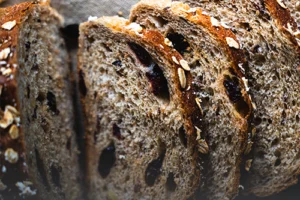 Pan integral artesanal con costra de granola y semillas, tajado sobre una tabla de madera rústica en Panadería El Molino, Cali.