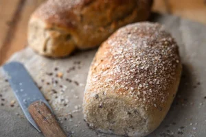 Hogazas de pan integral multicereal artesanal enriquecido con un 20% de quinua, recién horneado en Panadería El Molino, Cali.