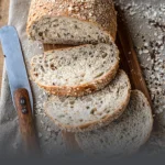 Hogaza de pan integral multicereal artesanal rebanado, mostrando su miga rica en semillas y cubierta de avena, elaborado en Panadería El Molino, Cali.