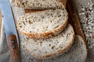 Hogaza de pan integral multicereal artesanal rebanado, mostrando su miga rica en semillas y cubierta de avena, elaborado en Panadería El Molino, Cali.
