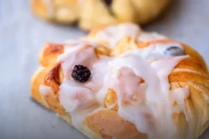 Mini pan danés artesanal con capas de hojaldre dorado y brillante sobre una mesa de madera clara en Panadería El Molino, Cali.