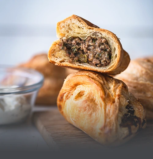 Pastel de carne tradicional, masa de hojaldre dorada y crujiente con relleno salado, horneado en Panadería El Molino, Cali.