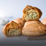Pastel de pollo tradicional, masa de hojaldre crujiente y dorada con un jugoso relleno salado, horneado en Panadería El Molino, Cali.