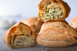 Pastel de pollo tradicional, masa de hojaldre crujiente y dorada con un jugoso relleno salado, horneado en Panadería El Molino, Cali.