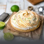 Pie de limón entero artesanal coronado con abundante merengue tostado y ralladura de limón fresco, sobre una tabla rústica en Panadería El Molino, Cali.
