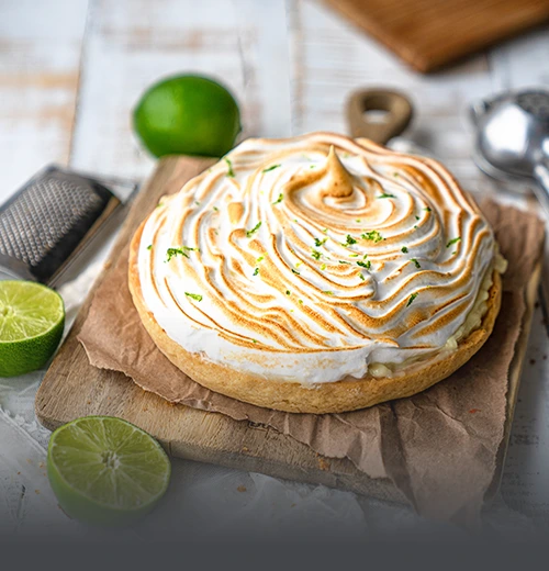 Pie de limón entero artesanal coronado con abundante merengue tostado y ralladura de limón fresco, sobre una tabla rústica en Panadería El Molino, Cali.