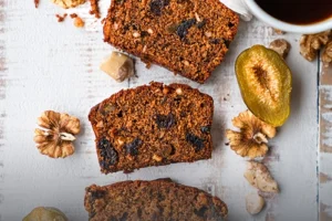 Tres porciones de cake negro artesanal con frutos secos, nueces y ciruelas, servidas sobre una mesa rústica junto a una taza de café, en Panadería El Molino, Cali.