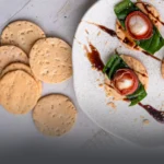 Tostadas de ajonjolí artesanales y crujientes, cubiertas de semillas, presentadas sobre una superficie de madera rústica en Panadería El Molino.
