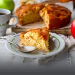 Porción individual de tarta vienesa de manzana artesanal servida en un plato con el logo de Panadería El Molino, acompañada de la tarta entera y café en Cali.