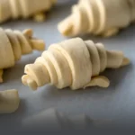 Bandeja con masa cruda de auténtico croissant parisino, listo para hornear en casa, elaborado por Panadería El Molino en Cali.