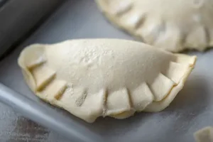 Bandeja con empanadas artesanales crudas rellenas de ricota y espinaca, listas para hornear en casa, elaboradas por Panadería El Molino en Cali.