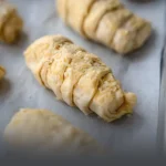 Bandeja con palitos de queso crudos en masa de hojaldre, listos para hornear en casa, elaborados por Panadería El Molino en Cali.