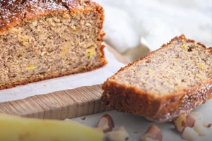 Porción de cake artesanal de banano y nuez siendo cortada, servido junto a bananos frescos y trozos de nuez en Panadería El Molino, Cali.