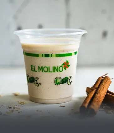 Vaso de avena tradicional y natural de Panadería El Molino en Cali, bebida refrescante acompañada de canela.