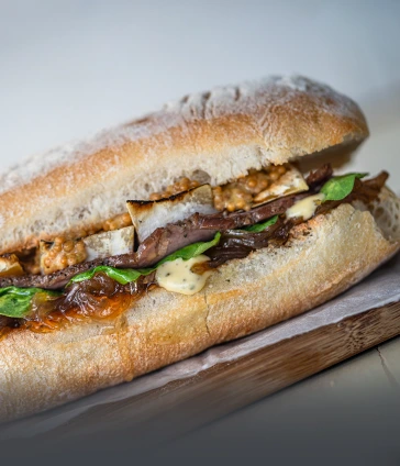 Delicioso sándwich de roast beef preparado con pan artesanal fresco, vegetales crujientes y aderezos. Una opción de almuerzo nutritivo en Panadería El Molino, Universidad Javeriana Cali.